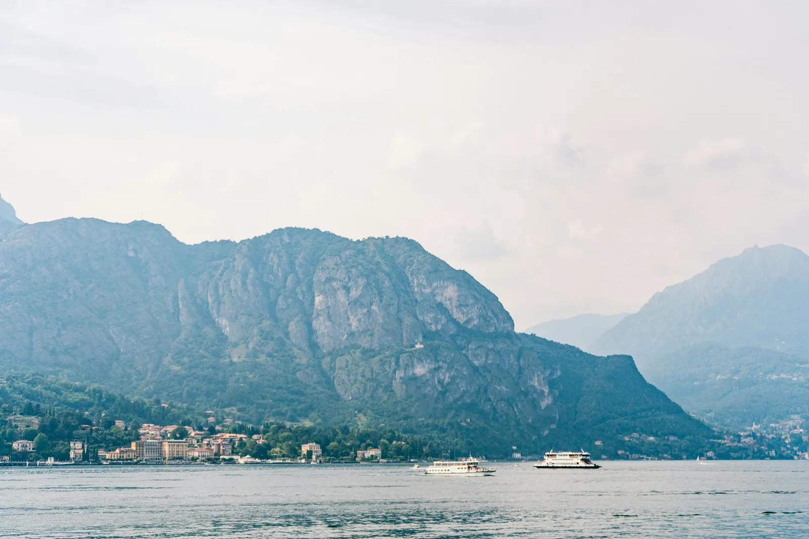 Boats on Lake Como beneath wooded mountains